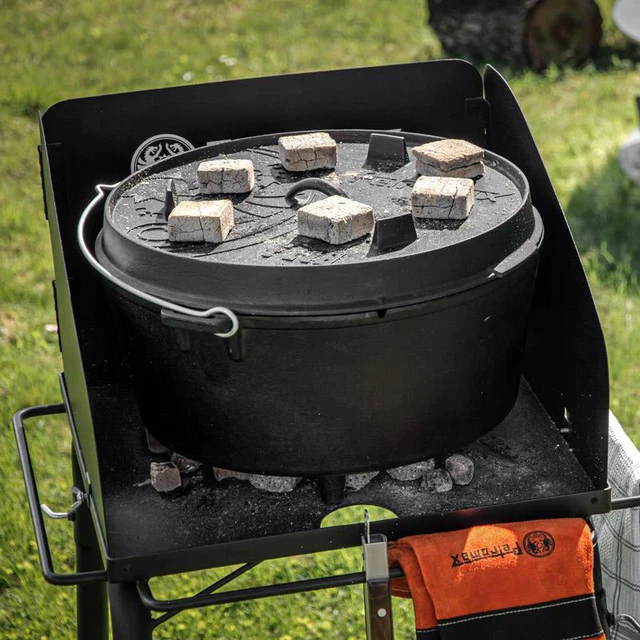 ein Feuertopf mit heißen Briketts auf einem kleinen Feuertisch auf einer Wiese