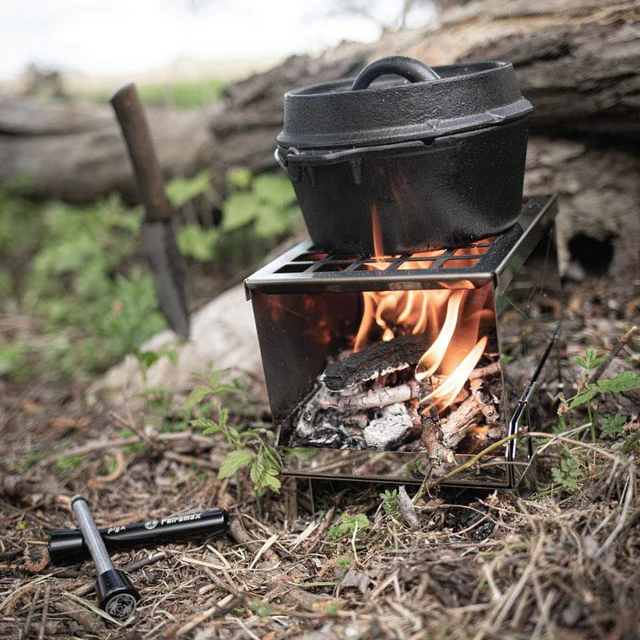 kleiner Dutch Oven über offenem Feuer und ein Jagdmesser in der Natur